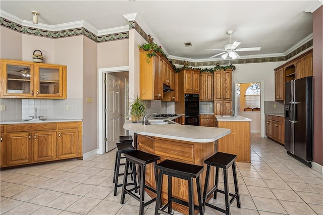 kitchen with a breakfast bar, black appliances, ceiling fan, and crown molding