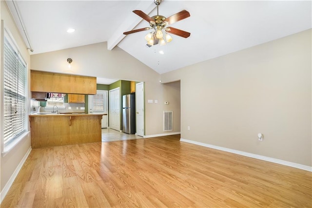 kitchen with visible vents, a peninsula, freestanding refrigerator, beamed ceiling, and open floor plan