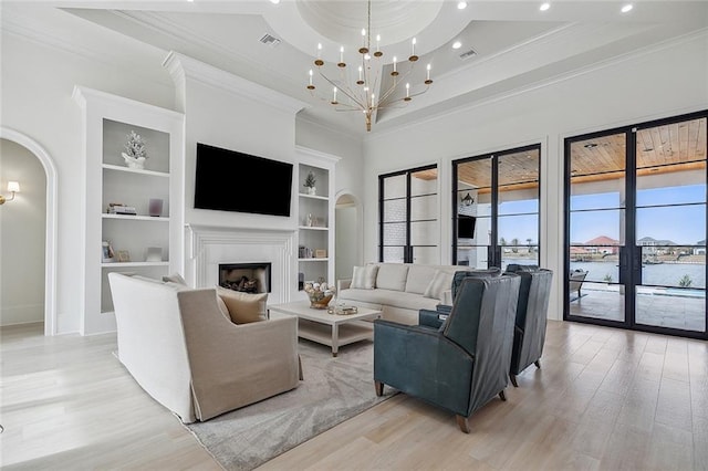 living room with a notable chandelier, light wood-type flooring, built in shelves, and ornamental molding