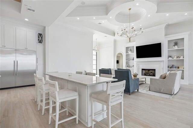 kitchen with hanging light fixtures, a water view, ornamental molding, and light hardwood / wood-style flooring