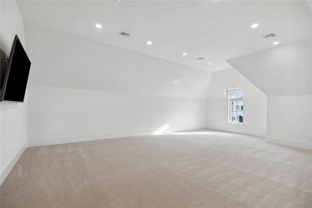 bonus room with lofted ceiling and light carpet