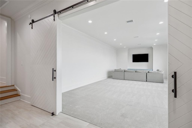 unfurnished living room with light carpet, crown molding, and a barn door