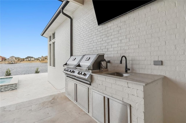 view of patio / terrace with area for grilling, sink, a water view, and exterior kitchen