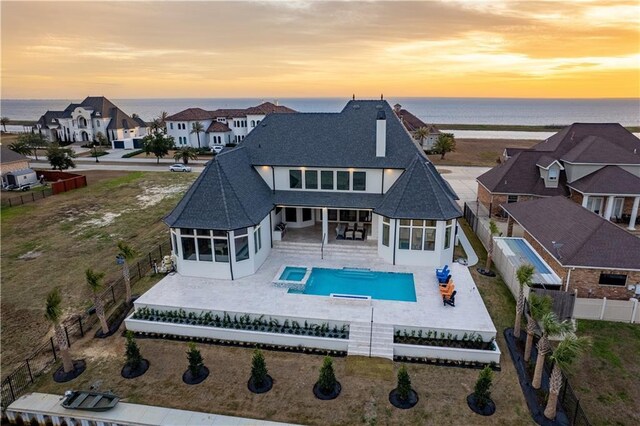 back house at dusk with a patio and a water view