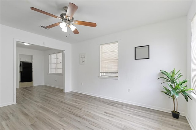 unfurnished room featuring a healthy amount of sunlight, ceiling fan, and light hardwood / wood-style floors