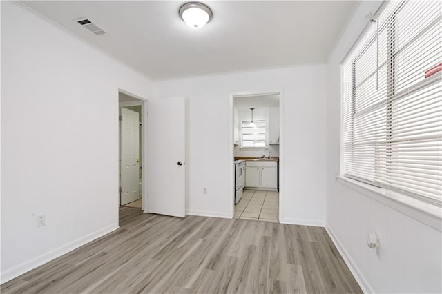 unfurnished bedroom with sink, connected bathroom, crown molding, and light hardwood / wood-style flooring