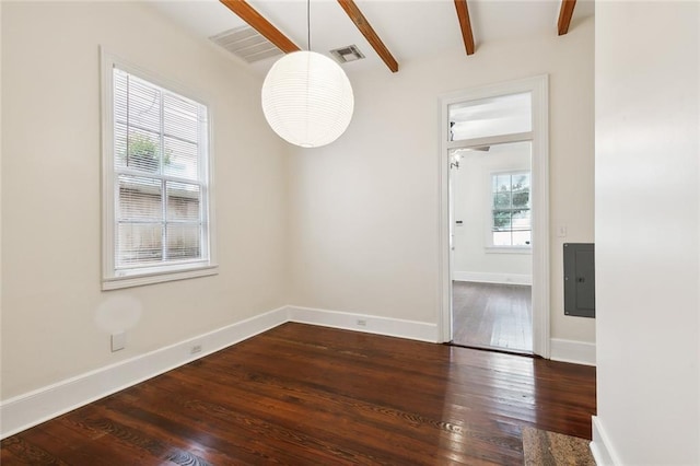 spare room featuring a wealth of natural light, beam ceiling, dark hardwood / wood-style floors, and electric panel