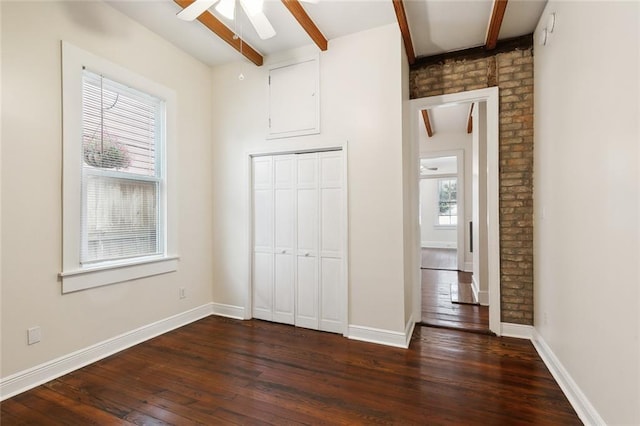 unfurnished bedroom with a closet, ceiling fan, beamed ceiling, and dark wood-type flooring