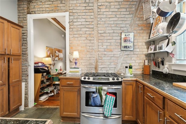 kitchen featuring dark wood-type flooring, brick wall, stainless steel range with gas cooktop, and vaulted ceiling