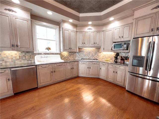 kitchen with sink, ornamental molding, stainless steel appliances, and light hardwood / wood-style floors