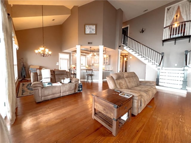 living room featuring hardwood / wood-style flooring, high vaulted ceiling, and an inviting chandelier