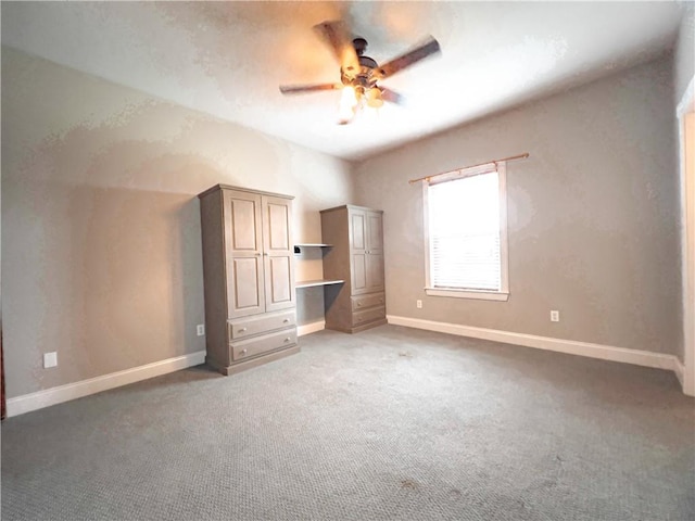 unfurnished bedroom featuring ceiling fan, built in desk, and dark carpet