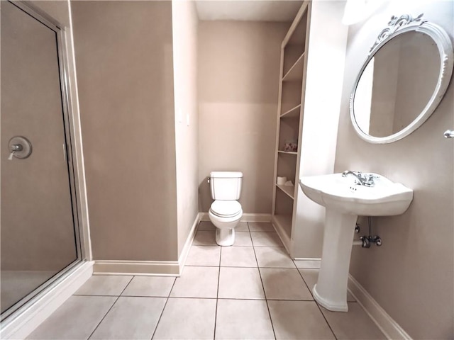 bathroom featuring tile patterned floors, toilet, and a shower with shower door