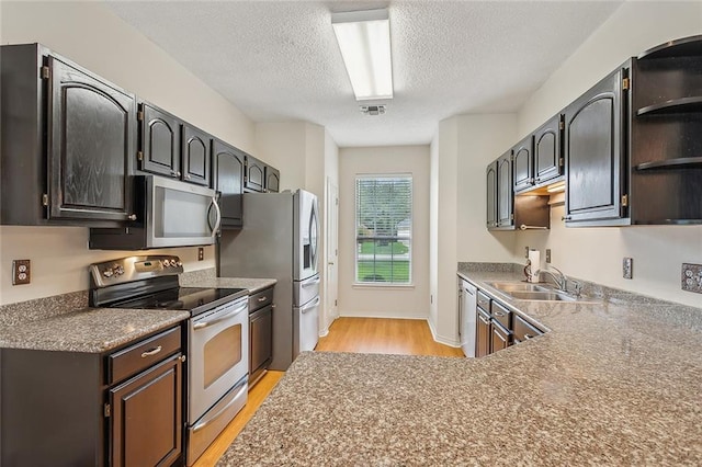 kitchen with light hardwood / wood-style floors, a textured ceiling, stainless steel appliances, sink, and dark brown cabinetry