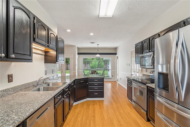 kitchen featuring pendant lighting, a textured ceiling, sink, appliances with stainless steel finishes, and light hardwood / wood-style floors