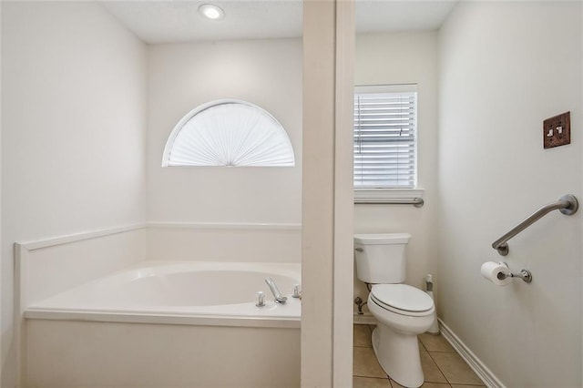 bathroom with tile patterned flooring, a healthy amount of sunlight, toilet, and a tub