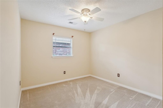 spare room with a textured ceiling, light colored carpet, and ceiling fan