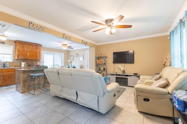 tiled living room with ceiling fan, ornamental molding, and plenty of natural light