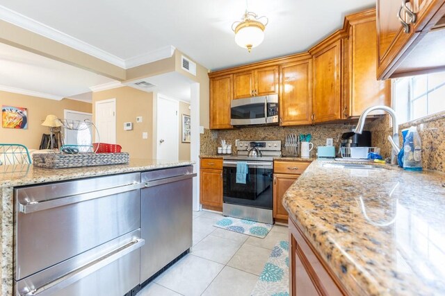 kitchen with sink, light stone counters, ornamental molding, and stainless steel appliances