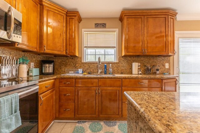 kitchen with decorative backsplash, sink, light tile patterned floors, crown molding, and appliances with stainless steel finishes