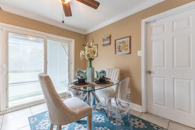 tiled dining space with ceiling fan and crown molding