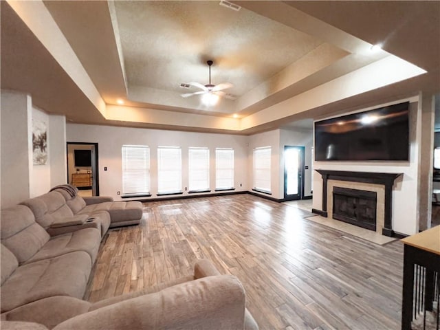 living room with hardwood / wood-style floors, a tray ceiling, and ceiling fan