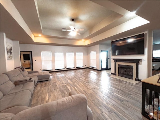 living room featuring ceiling fan, a tray ceiling, and hardwood / wood-style floors