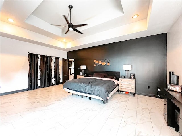 bedroom with ceiling fan and a raised ceiling