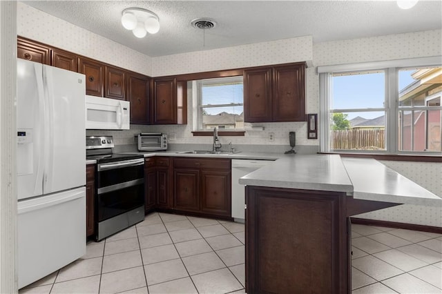 kitchen featuring light tile patterned floors, white appliances, plenty of natural light, and sink