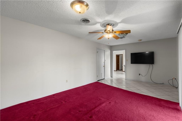 spare room featuring a textured ceiling, ceiling fan, and light carpet