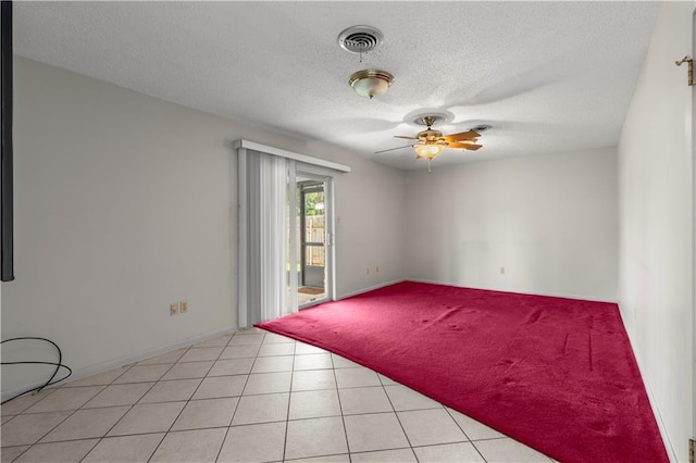 empty room with ceiling fan, light tile patterned flooring, and a textured ceiling