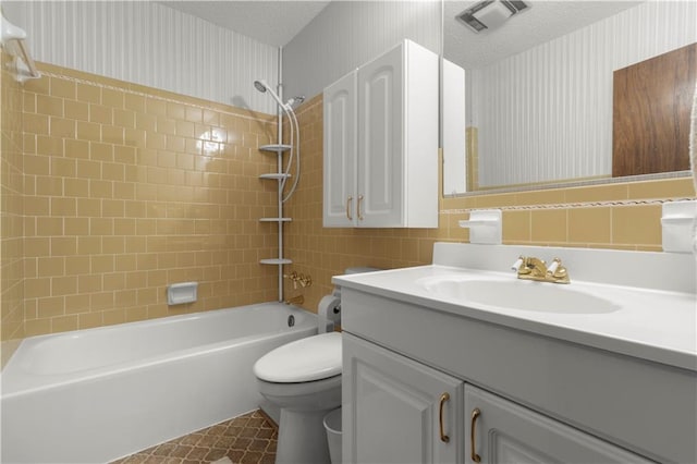 full bathroom with tiled shower / bath combo, vanity, toilet, and a textured ceiling