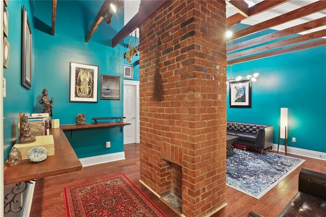 bathroom featuring a brick fireplace, beamed ceiling, and hardwood / wood-style floors