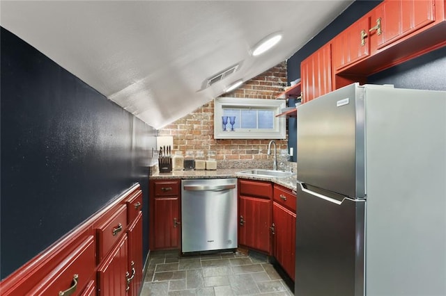 kitchen with appliances with stainless steel finishes, sink, and brick wall