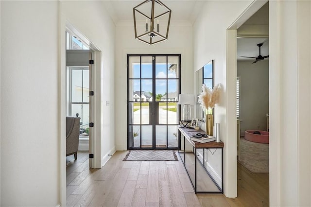 doorway to outside featuring light hardwood / wood-style floors, ceiling fan, and crown molding