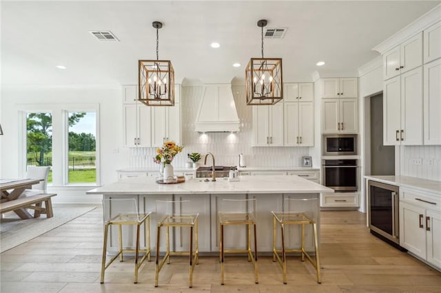 kitchen featuring a kitchen island with sink, a kitchen bar, stainless steel appliances, and wine cooler