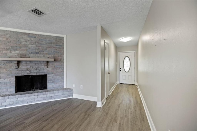 foyer entrance featuring hardwood / wood-style floors, a textured ceiling, and a brick fireplace