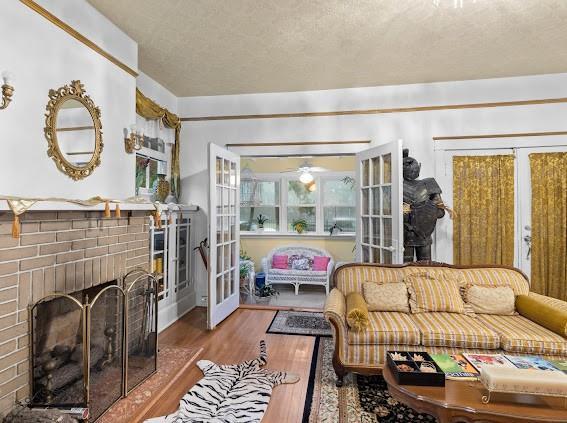 living room featuring a brick fireplace, french doors, and wood finished floors