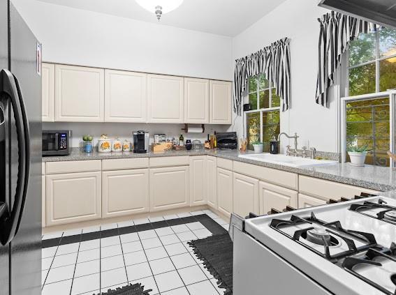 kitchen with sink, light tile patterned floors, and appliances with stainless steel finishes