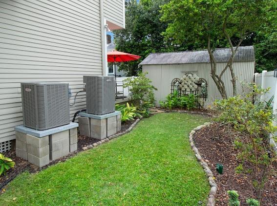 view of yard featuring an outbuilding, central AC, fence, and a shed