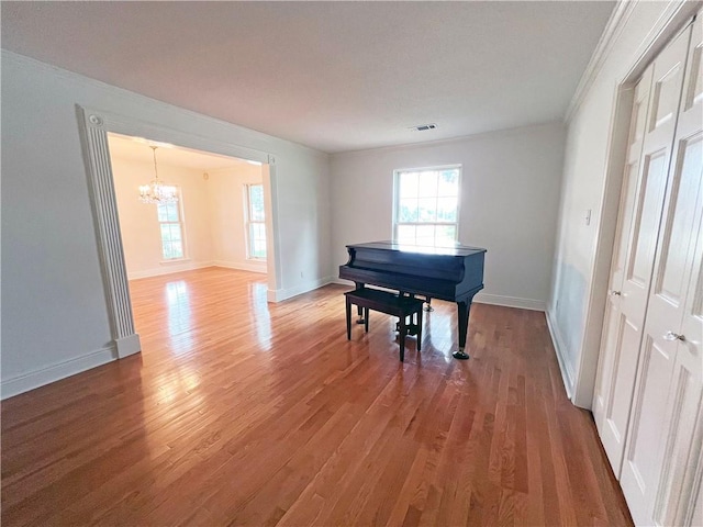 misc room featuring hardwood / wood-style flooring, an inviting chandelier, and crown molding