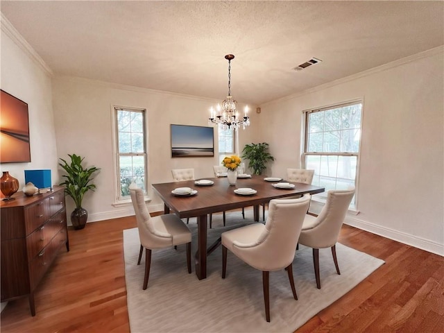 dining area featuring ornamental molding, plenty of natural light, hardwood / wood-style floors, and an inviting chandelier