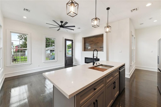 kitchen featuring decorative light fixtures, a center island with sink, dark wood-type flooring, sink, and ceiling fan