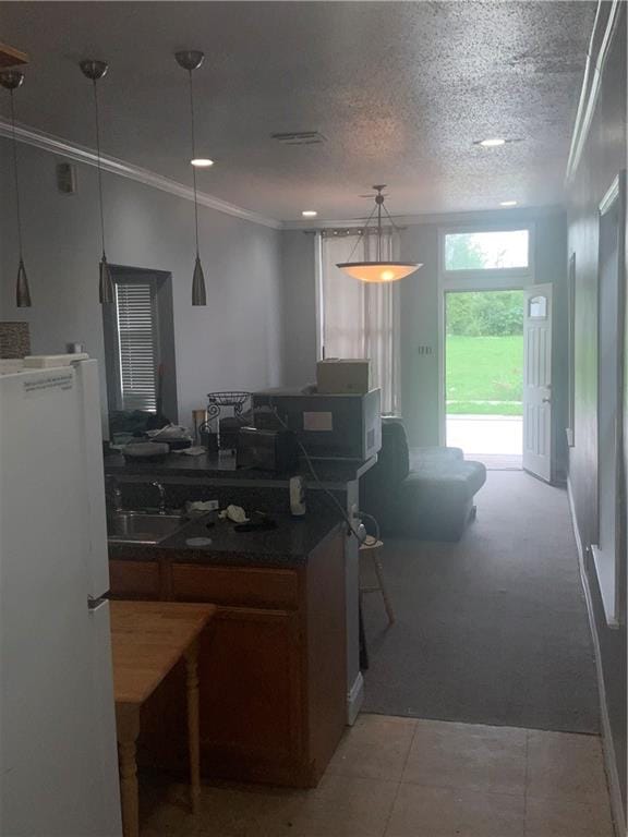 kitchen featuring white fridge, decorative light fixtures, crown molding, sink, and carpet flooring