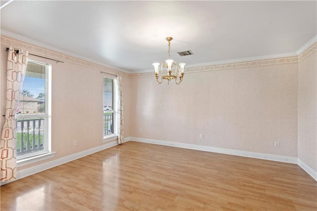 empty room featuring light hardwood / wood-style flooring, ornamental molding, a notable chandelier, and a healthy amount of sunlight