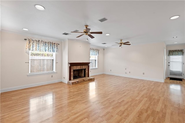 unfurnished living room with light wood-type flooring, crown molding, a brick fireplace, and ceiling fan