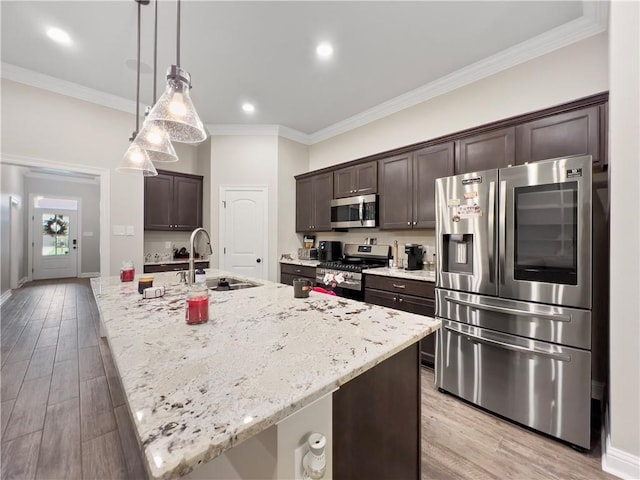 kitchen with an island with sink, appliances with stainless steel finishes, hanging light fixtures, and sink