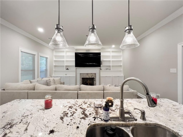 kitchen with hanging light fixtures, ornamental molding, sink, and light stone counters