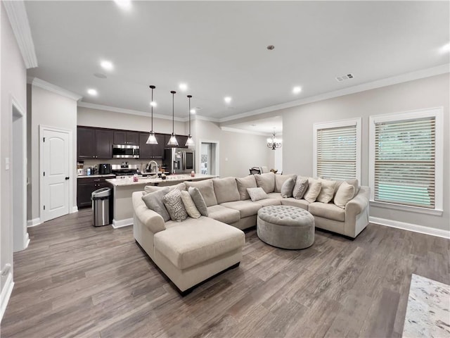 living room with wood-type flooring, an inviting chandelier, and crown molding