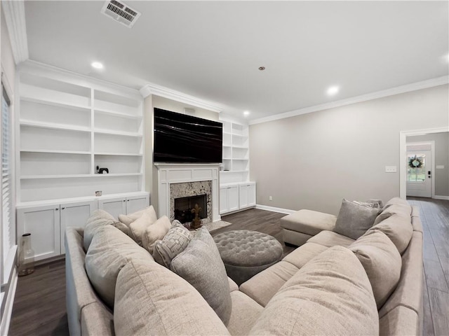 living room featuring built in shelves, ornamental molding, a premium fireplace, and dark hardwood / wood-style flooring